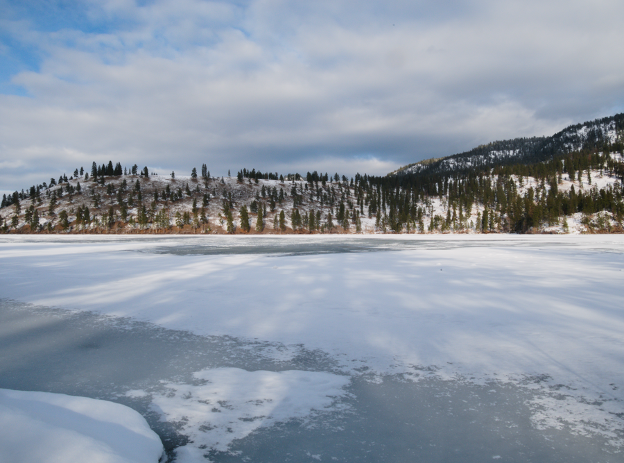 View across frozen Kalamalka Lake with mountains in the background.