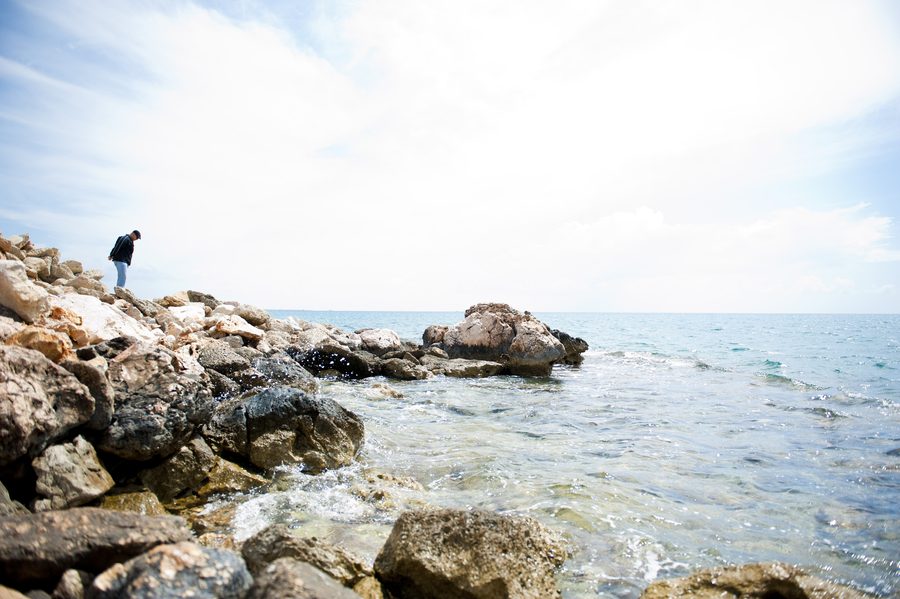 A visitor walks along rocks beside the Mediterranean coast in Mersin Province, Turkey