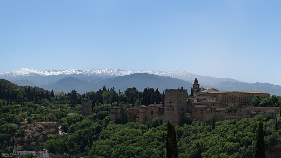 Panoramic view of the Alhambra in Granada against a mountain backdrop.