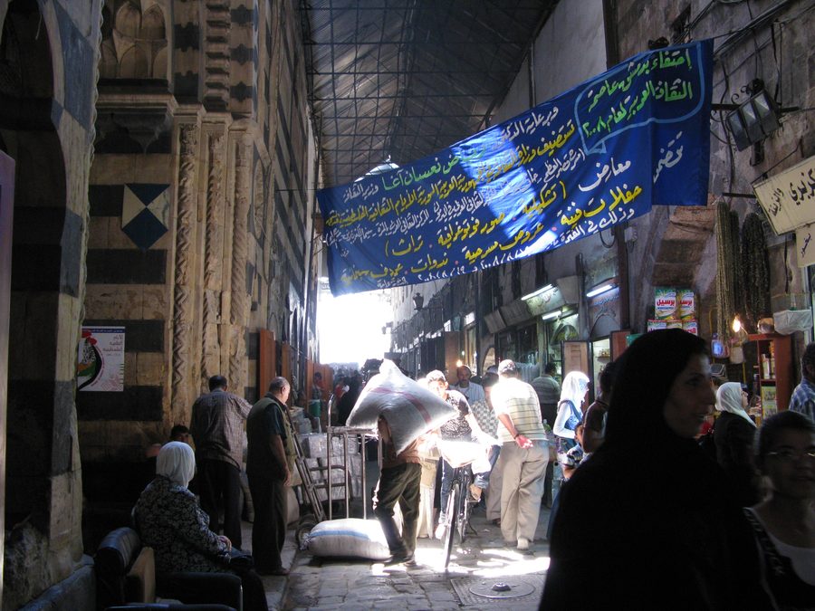 Historic souk in the old town of Damascus with people between traditional buildings
