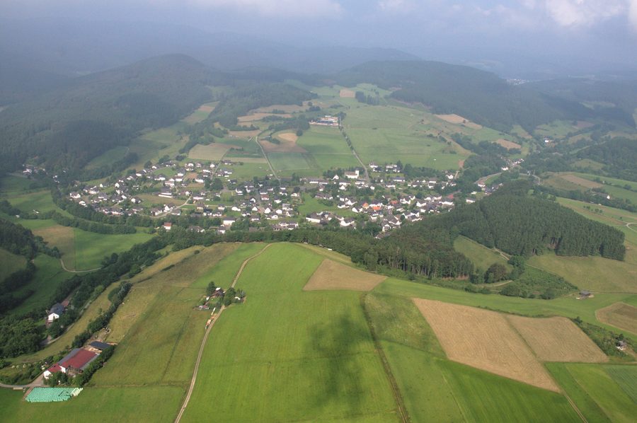 Aerial view of Hallenberg-Liesen with open land and wooded slopes in the background