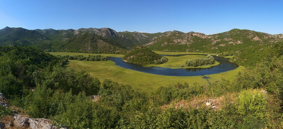Distinctive bend in the Crnojević River between green karst slopes