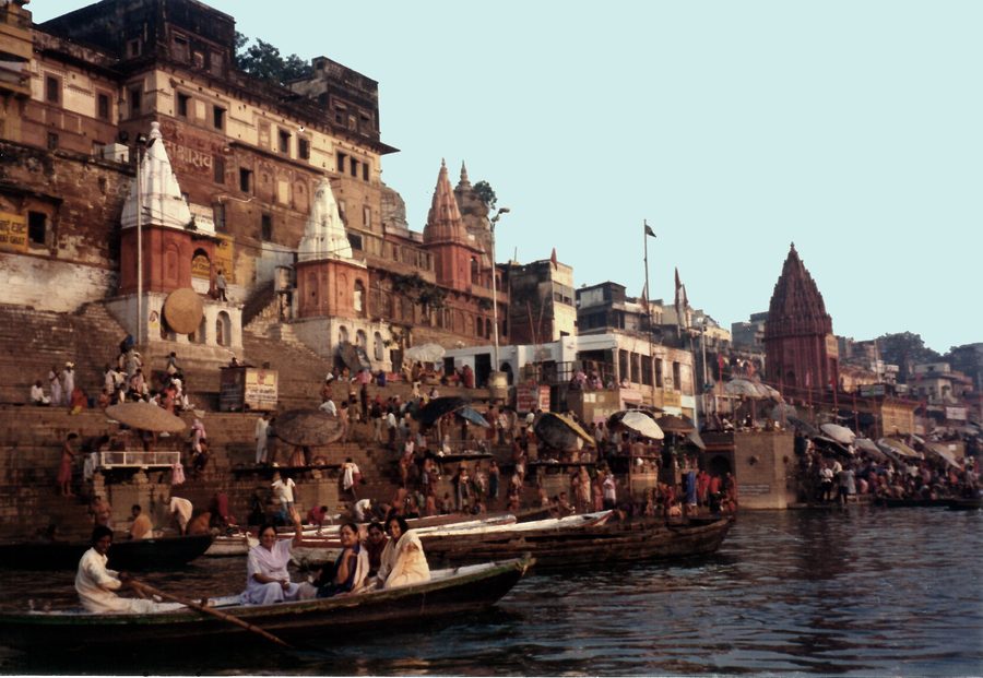 The Ganges at dawn beside the Varanasi ghats, with boats on the river.