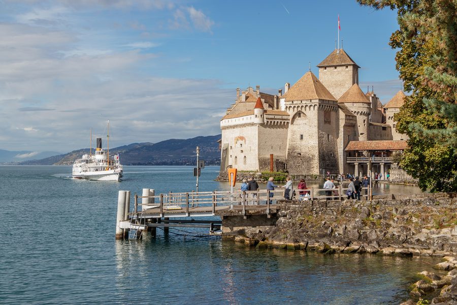 Chillon Castle on the shore of Lake Geneva as a historic steamboat approaches.