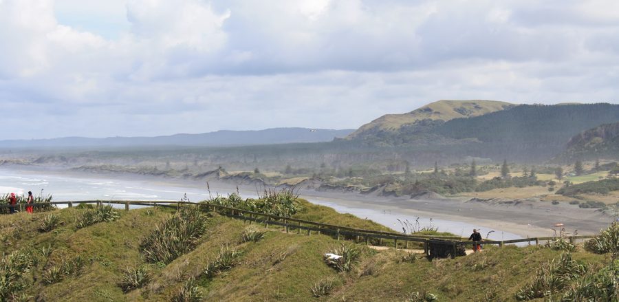 Muriwai Beach with black sand and rocky coastline in New Zealand